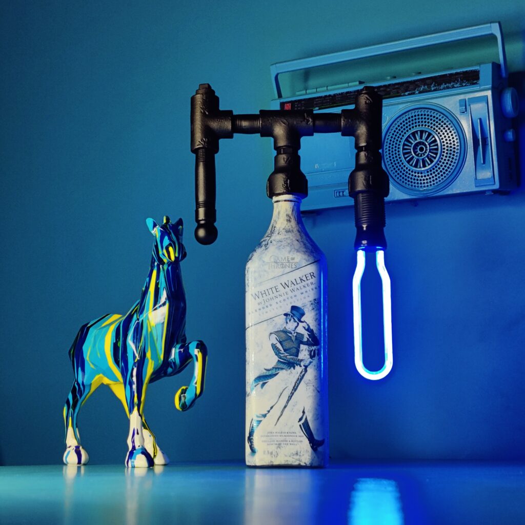 Lamp with Industrial Grade Iron pipes coupled with a Blue LED bulb and a Johnnie Walker White Walker Empty Bottle used as the base